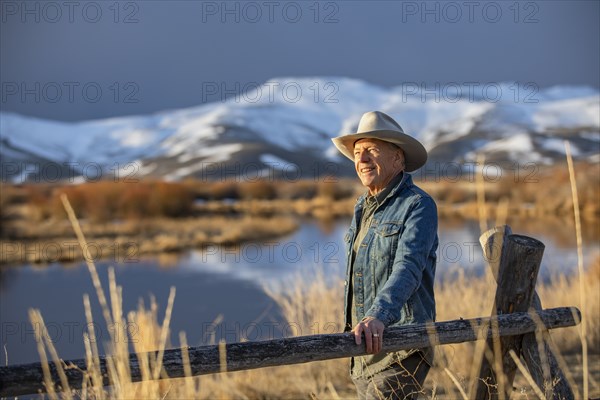 USA, Idaho, Sun Valley, Senior man leaning against fence looking at view