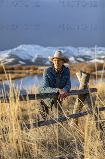 USA, Idaho, Sun Valley, Senior man leaning against fence looking at view