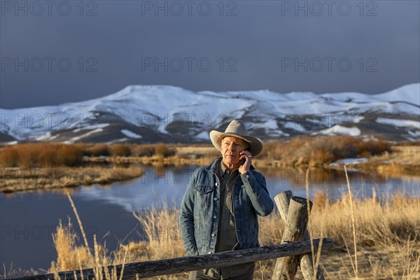 USA, Idaho, Sun Valley, Senior man in cowboy using smartphone