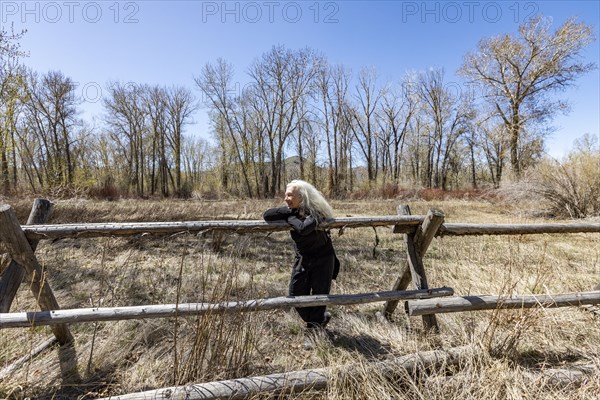 USA, Idaho, Bellevue, Senior woman relaxing on rustic rail fence