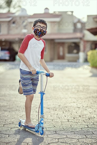 Mexico, Zapopan, Boy with face mask riding scooter