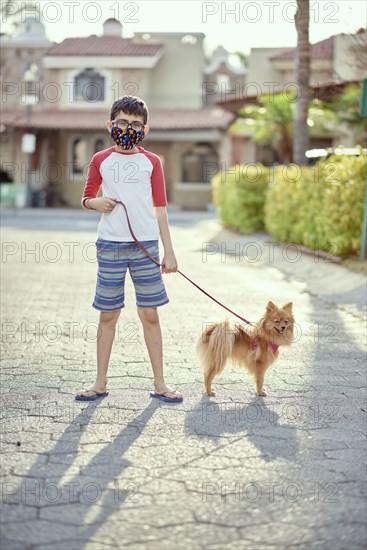 Mexico, Zapopan, Boy with face mask walking dog