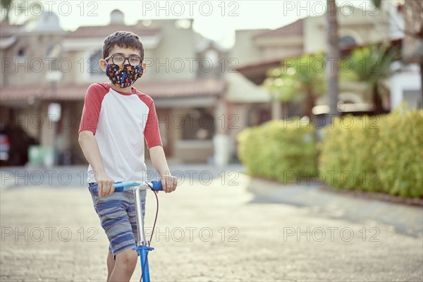 Mexico, Zapopan, Boy with face mask riding scooter