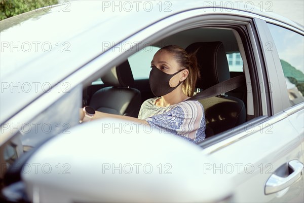 Woman with face mask driving car