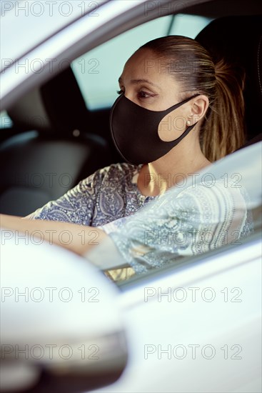 Woman with face mask driving car