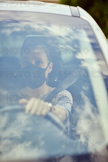 Woman with face mask driving car