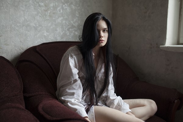 Portrait of young woman sitting in armchair