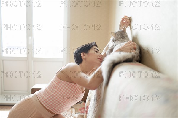 Young woman stroking cat on sofa