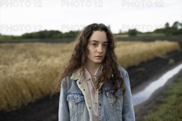 Russia, Omsk, Portrait of young woman with brown hair standing in field