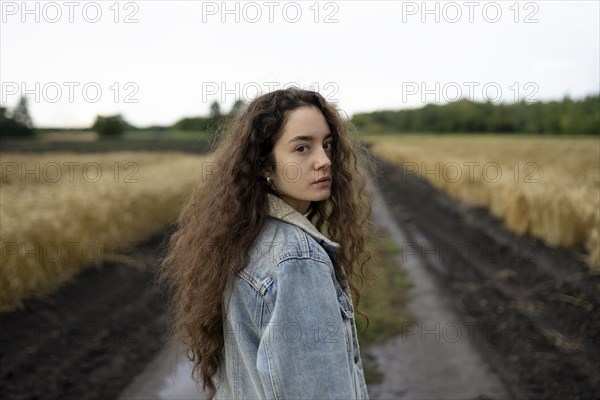 Russia, Omsk, Portrait of young woman with brown hair standing in field