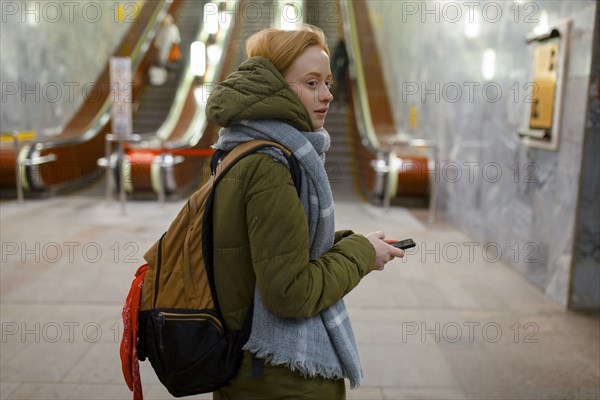 Russia, Novosibirsk, Young woman standing by escalator in subway