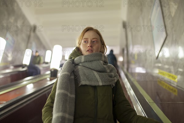 Russia, Novosibirsk, Young woman standing on escalator