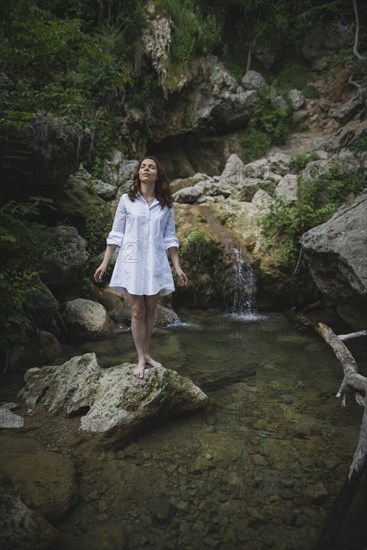 Ukraine, Crimea, Young woman standing on rock near waterfall