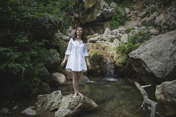 Ukraine, Crimea, Young woman standing on rock near waterfall