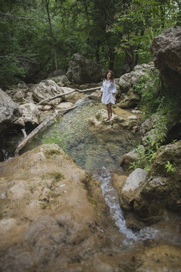 Ukraine, Crimea, Young woman standing on rock in river