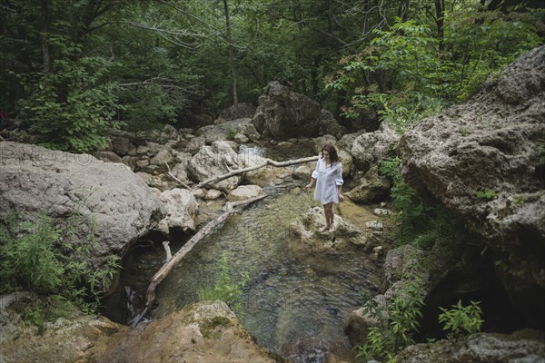 Ukraine, Crimea, Young woman standing on rock in river