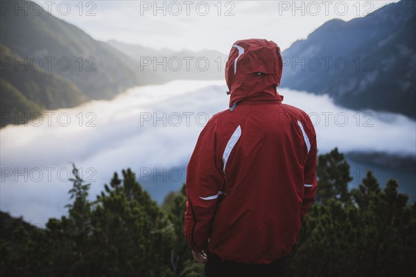 Austria, Plansee, Rear view of man in red jacket standing in Austrian Alps