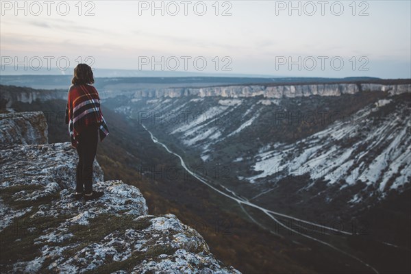 Ukraine, Crimea, Young woman covered with plaid looking at canyon