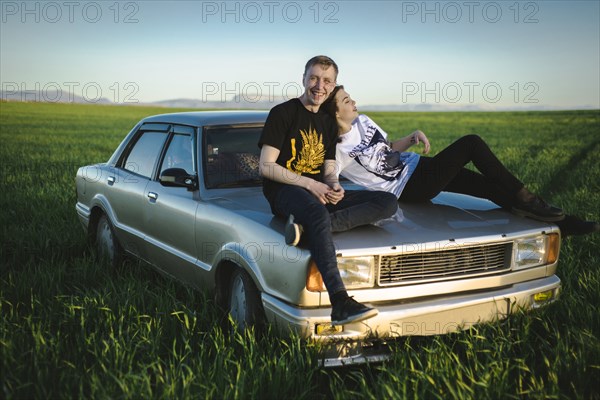 Ukraine, Crimea, Couple sitting on old fashioned car in rural scenery