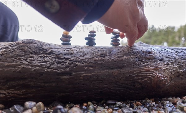 Orcas Island, Man arranging pebble sculpture on log