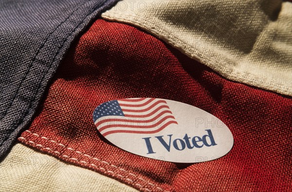 Close-up of I voted sticker on American flag