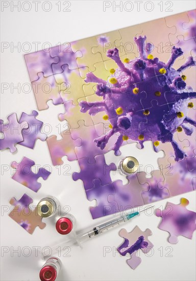 Studio shot of puzzle with Coronavirus model and vaccine vials and syringe