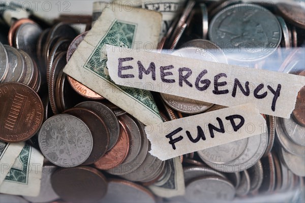 Close-up of coins and banknotes in jar labeled Emergency Found