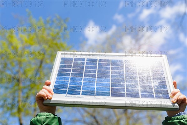 Close-up of boys (4-5) hands holding solar panel against sky