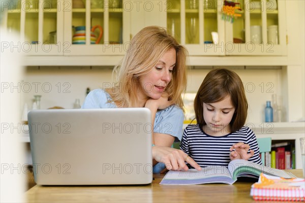Mother helping daughter (6-7) doing homework