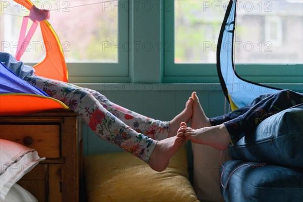 Brother (4-5) and sister (6-7) touching feet out of tents in playroom