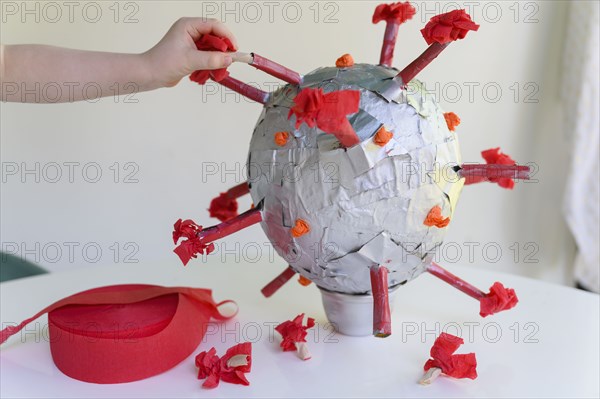 Girl (6-7) making papier mache model of coronavirus