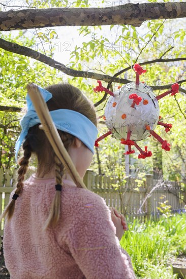 Girl (6-7) preparing to hit coronavirus shaped pinata