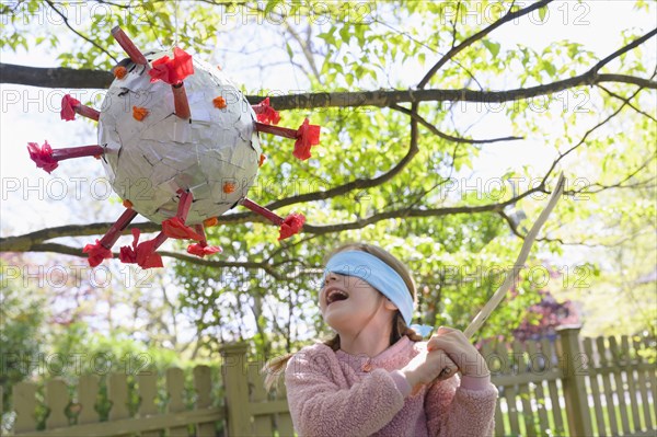 Girl (6-7) hitting coronavirus shaped pinata