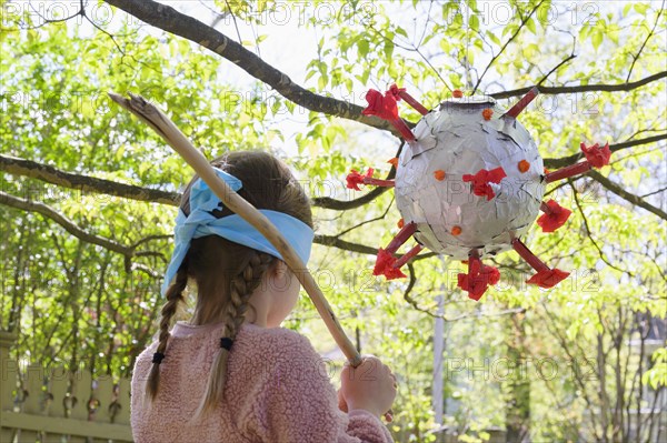 Girl (6-7) preparing to hit coronavirus shaped pinata