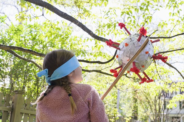 Girl (6-7) hitting coronavirus shaped pinata