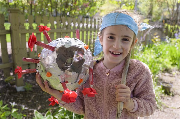 Smiling girl (6-7) holding coronavirus shaped pinata