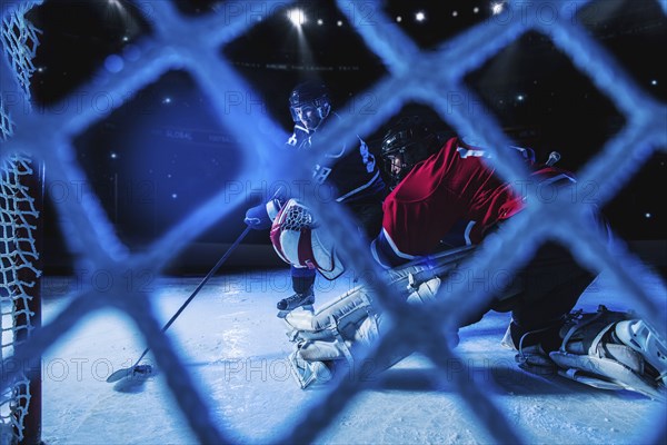 Hockey goalie defending net against forward