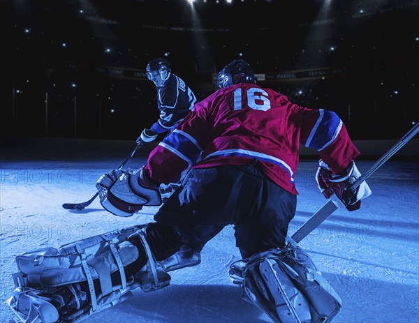 Hockey goalie in defensive position against forward