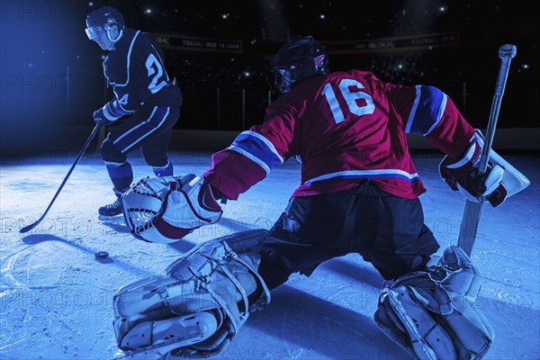 Hockey goalie in defensive position against forward