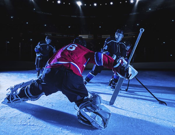 Hockey goalie in defensive position against forwards