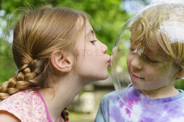 Girl kissing boy wearing bubble to socially distance