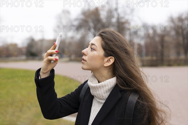 Russia, Chelyabinsk, Young woman looking at smartphone