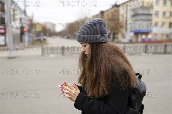 Russia, Chelyabinsk, Young woman using smartphone in city