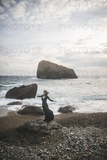 Ukraine, Crimea, Young woman standing on rocky beach