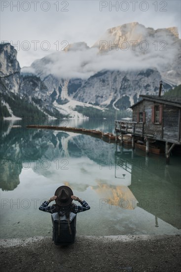 Italy, Woman sitting by Pragser Wildsee in Dolomites,