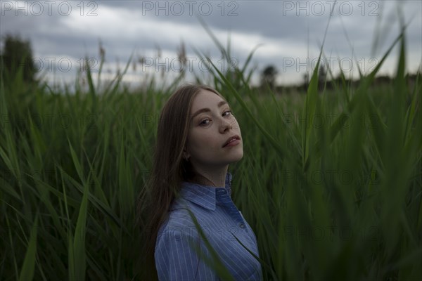 Russia, Omsk, Portrait of young woman in tall grass