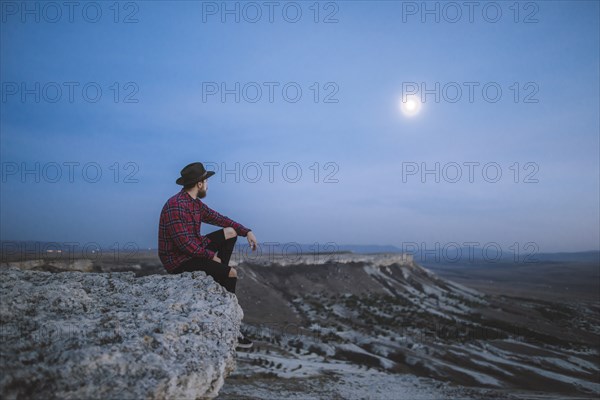 Ukraine, Crimea, Hiker sitting on edge of steep cliff near White Mountain