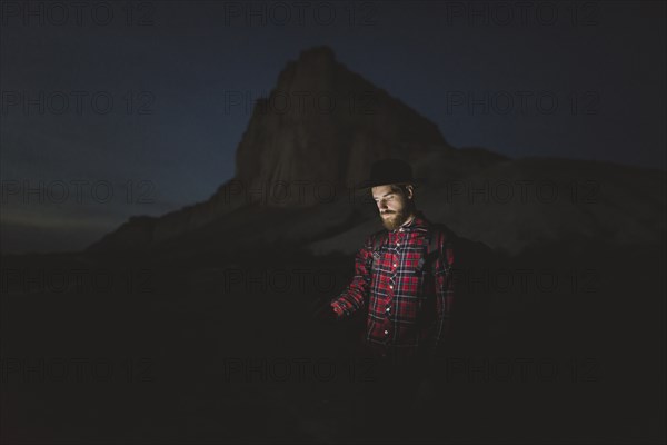 Ukraine, Crimea, Man in hat with glowing phone standing near White Mountain at night