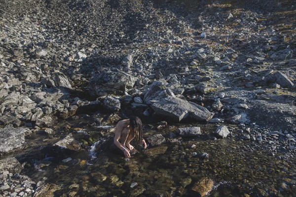 Norway, Man washing hair in mountain stream,