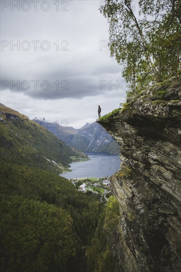 Norway, Geiranger, Man standing on edge of steep cliff above Geirangerfjord